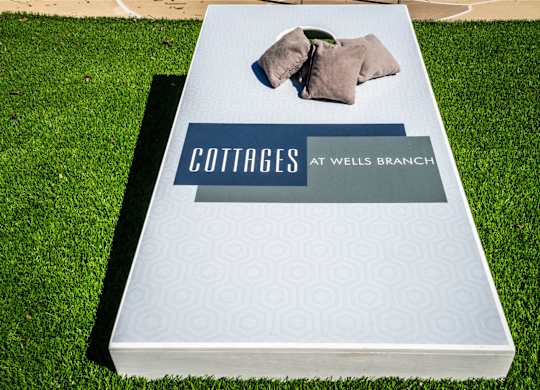 cottages at wells branch  cornhole board with logo