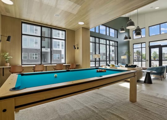 a pool table in a community room with windows
