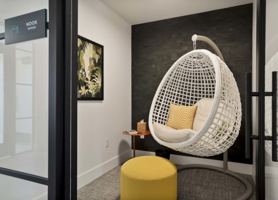 a white egg chair in a room with a black wall and a yellow stool