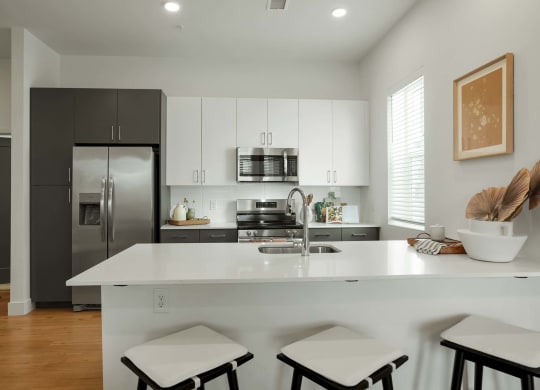 a kitchen with a white counter top and a stainless steel refrigerator