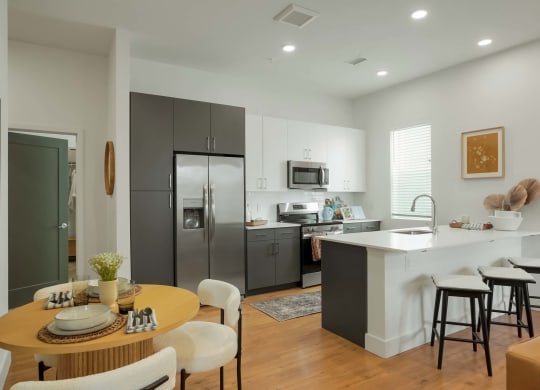 Colorado Apartments Near Denver Botanical Gardens - Edera Apartments - Kitchen With Grey and White Cabinetry, White Countertops, White Tile Backsplash, Luxury LVT Flooring, and Stainless Steel Appliances