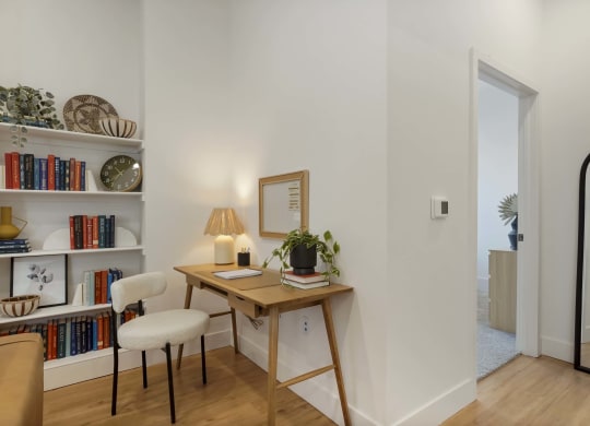 a desk with a chair and a mirror in a room with a bookshelf
