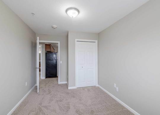 A room with a white door and a carpeted floor.
