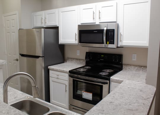 Enclave at Wolfchase Apartments in Cordova Tennessee photo of a kitchen with white cabinets and stainless steel appliances