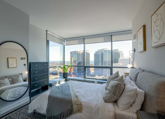 a bedroom with a large bed and a view of the city