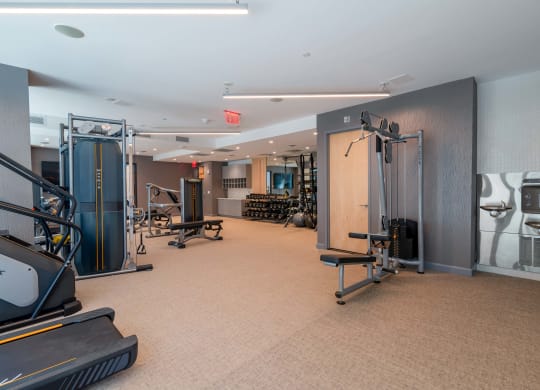 a gym with weights and cardio equipment on the floor and a mirrored wall