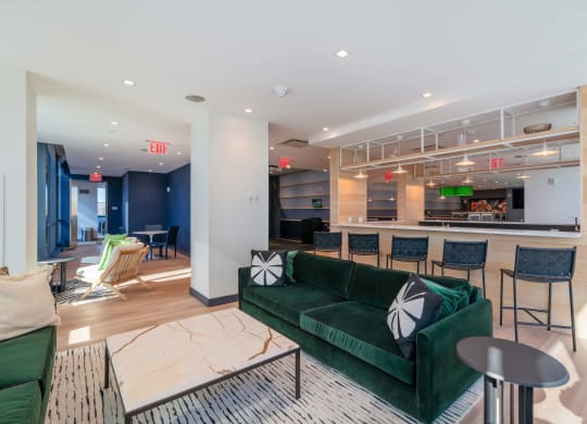 a living room with a green couch and a bar with chairs