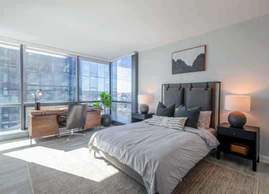 a bedroom with a bed and a desk with a large window