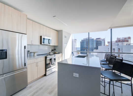 a kitchen with a large island and a stainless steel refrigerator