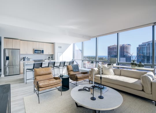a living room with a view of a kitchen and a large window