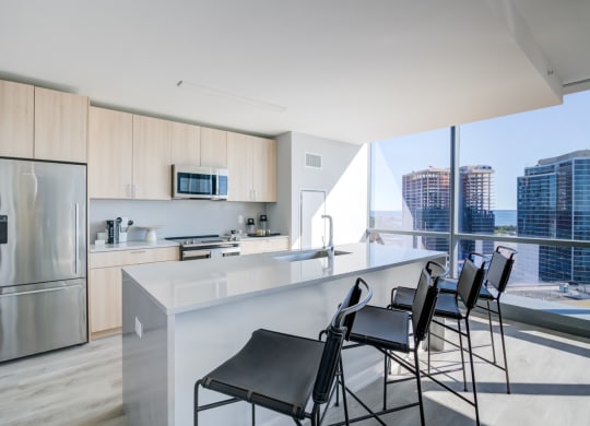 a kitchen with a counter and chairs in front of a window
