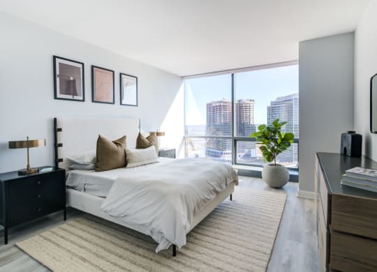 a bedroom with a large window and a bed and a rug