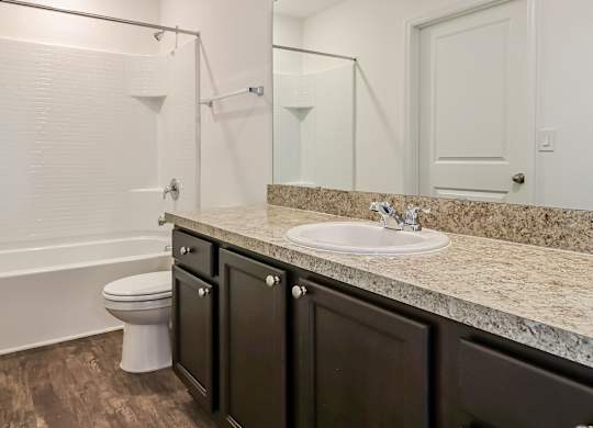 A white toilet sits in a bathroom with a marble countertop.