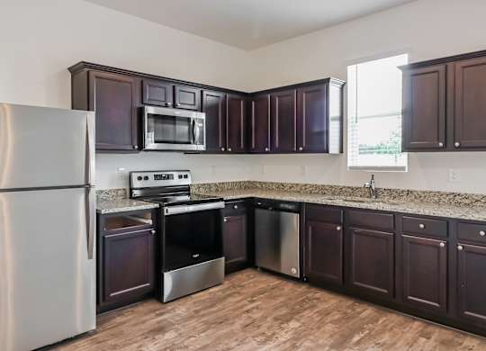 A kitchen with dark brown cabinets and a stainless steel refrigerator.
