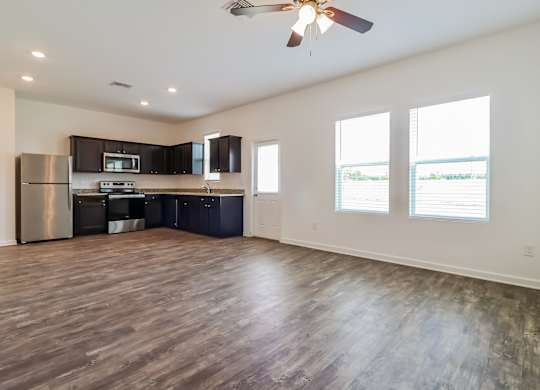 A spacious kitchen with dark wood floors and stainless steel appliances.