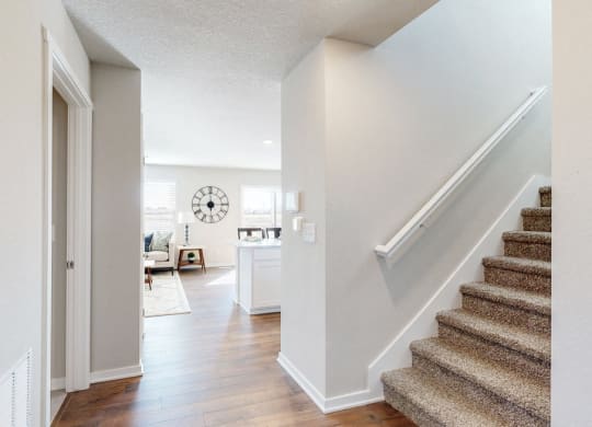 the entryway of a home with stairs and a clock on the wall