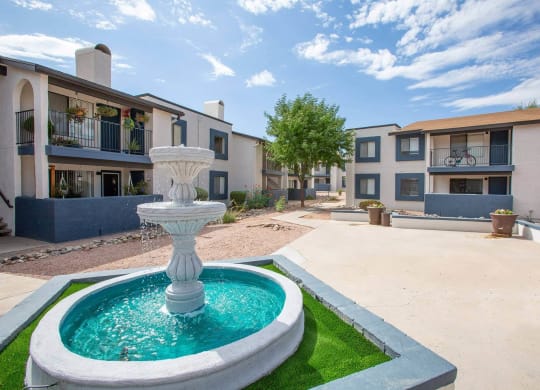 a fountain in the middle of a courtyard with apartments in the background
