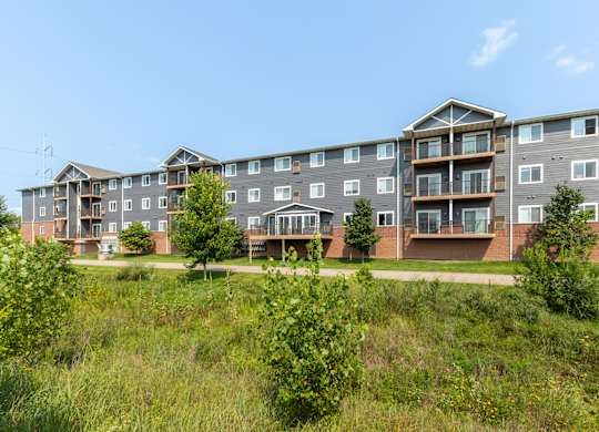 A large apartment complex with multiple balconies and greenery in the foreground.