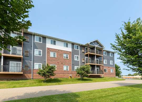 A large apartment building with multiple balconies and a driveway in front.