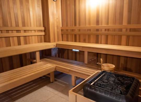 A sauna room with wooden benches and a bench with a black cover on it.