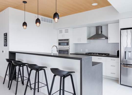 A modern kitchen with a bar area and stools.