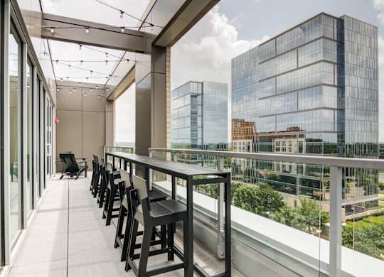 A balcony with a table and chairs overlooking a cityscape.