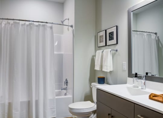 A white bathroom with a toilet, sink, and shower curtain.