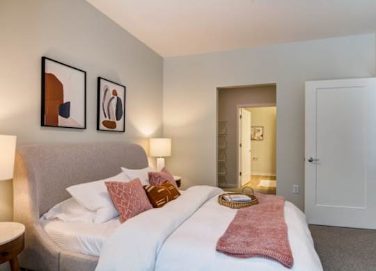 A bedroom with a bed, two lamps, and two pictures on the wall.