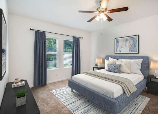 A bedroom with a bed, nightstands, and a ceiling fan.