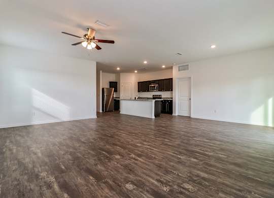 A spacious room with a ceiling fan and wooden flooring.