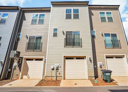 an apartment building with three garage doors and a sidewalk
