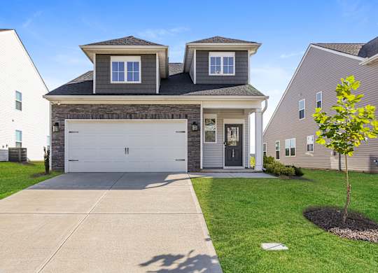 A two-story house with a garage and a tree in front.