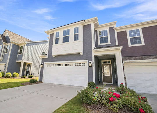 A house with a grey and brown exterior and a white garage door.