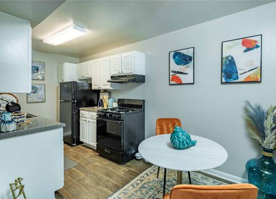 A kitchen with a black fridge and a white table.
