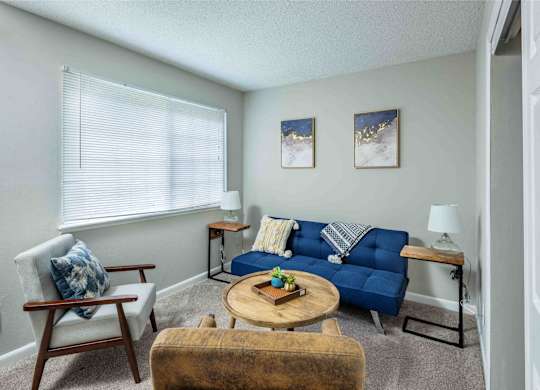 A living room with a blue couch and a wooden chair.