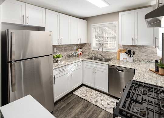 A modern kitchen with a stainless steel refrigerator and black stove top.