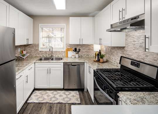 A kitchen with a stainless steel refrigerator, sink, and stove.