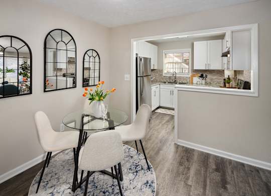 A kitchen with a table and chairs in the foreground and a refrigerator in the background.