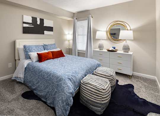 A bedroom with a bed, nightstand, and a painting on the wall.