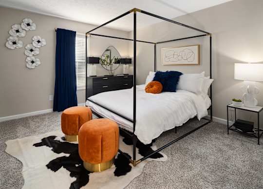 A bedroom with a four poster bed and a cowhide rug.