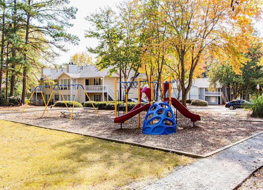 A playground with a red slide and a blue climbing structure.