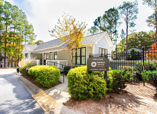 A sign in front of a house reads "Welcome to Harston Woods Leasing Office".