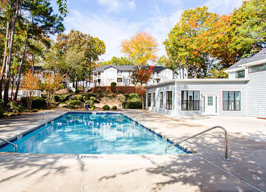 A small pool surrounded by trees and a house.