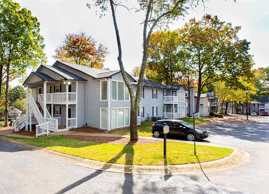 A white house with a grey roof is surrounded by trees.