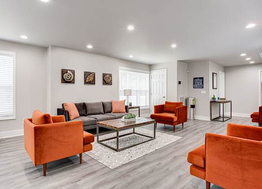 A living room with orange chairs and a grey couch.