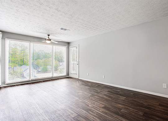A room with a ceiling fan and sliding glass doors.