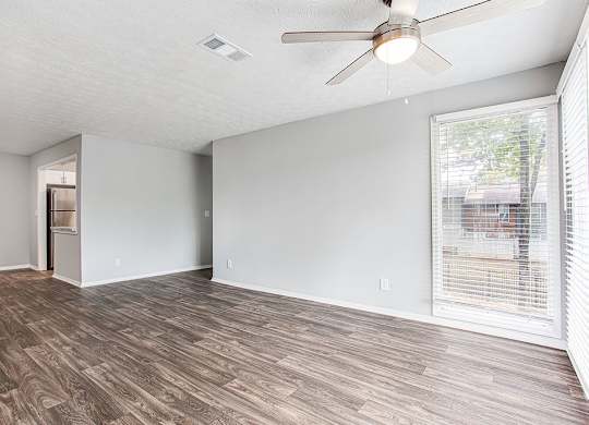 A room with a ceiling fan and wooden flooring.
