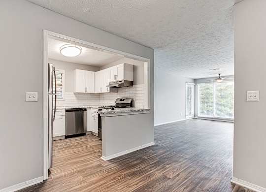 A kitchen with white cabinets and a wooden floor.