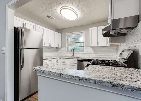 A kitchen with a refrigerator, stove, and white cabinets.