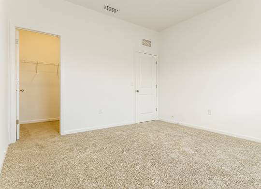 A room with a carpeted floor and a door on the left.
